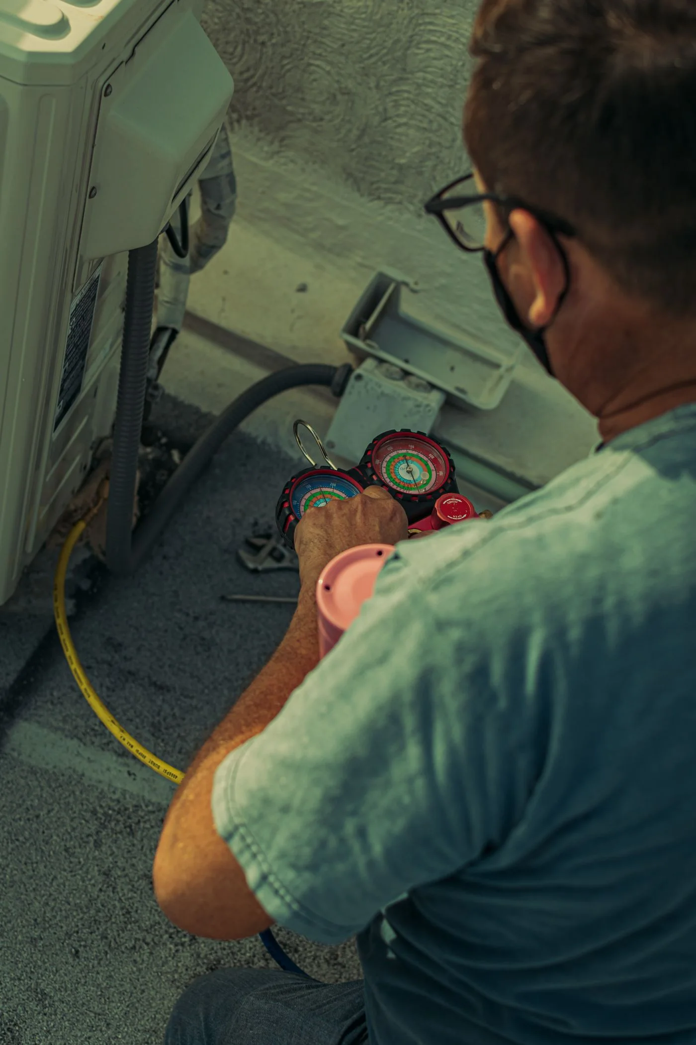 A technician inspecting an air-conditioning unit with pressure gauges