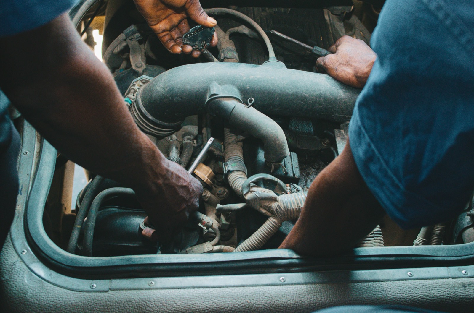 Close-up of two pairs of hands working with spanners on an engine