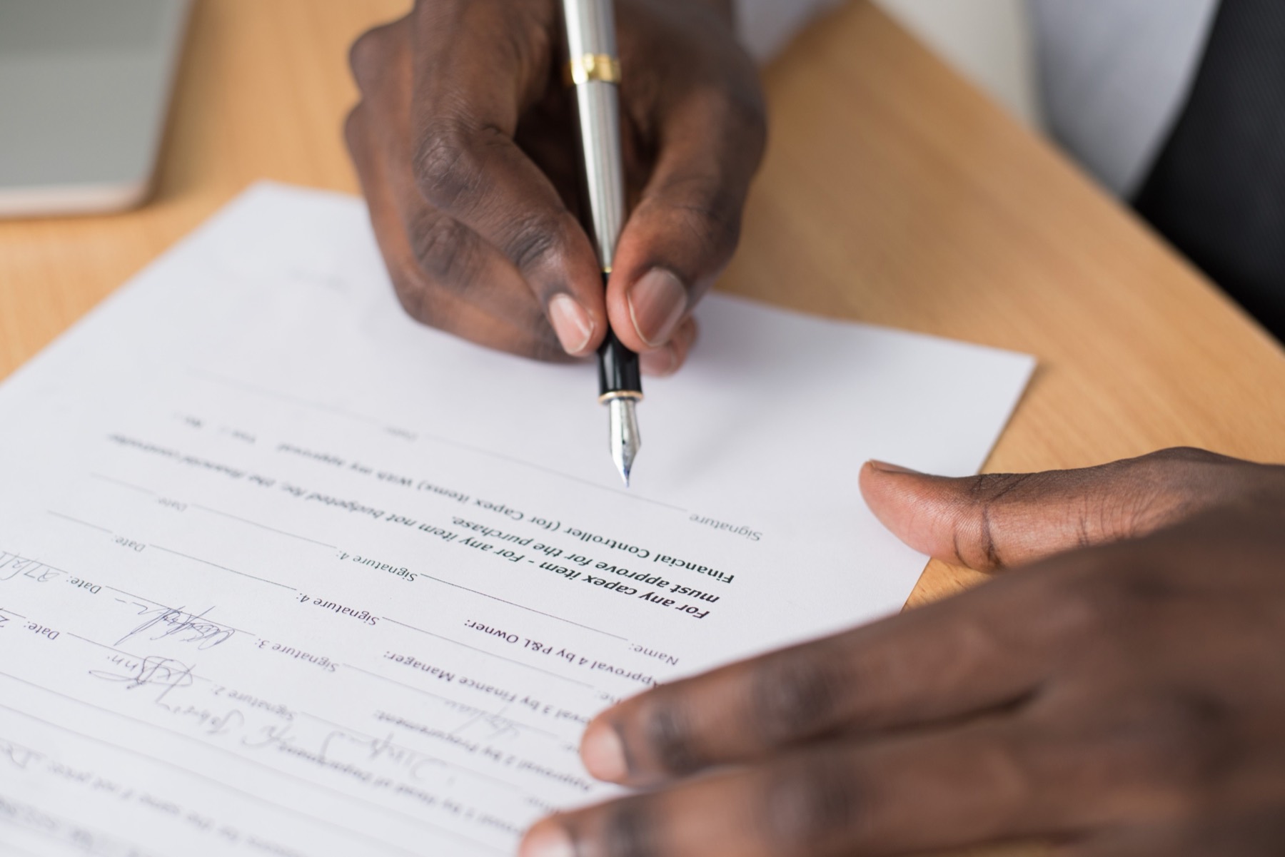 Close-up of a hand signing a printed document